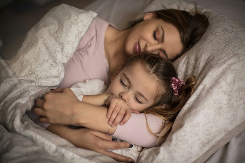 Mom and daughter sleeping in bed