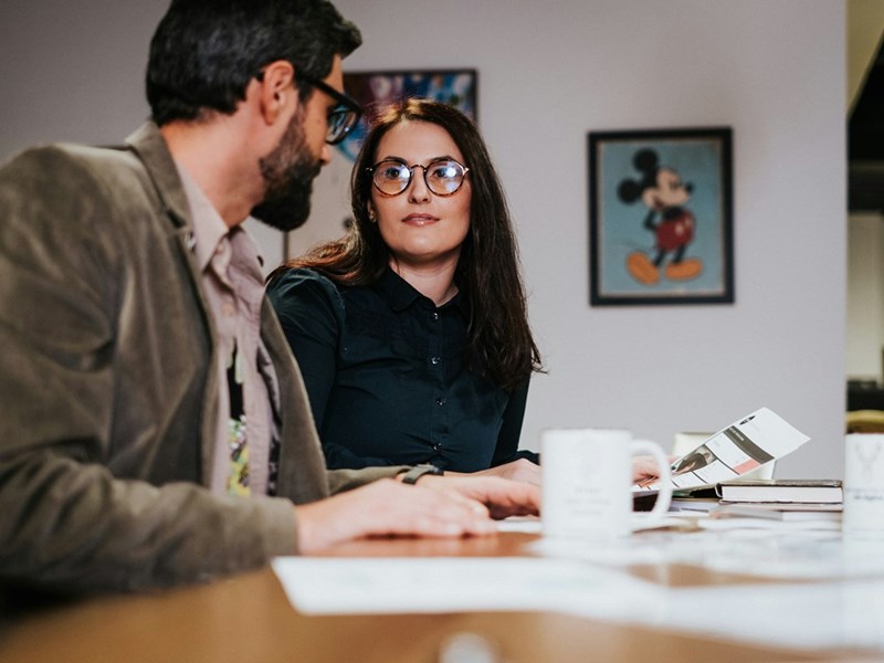 A female employee trains her male replacement at her desk
