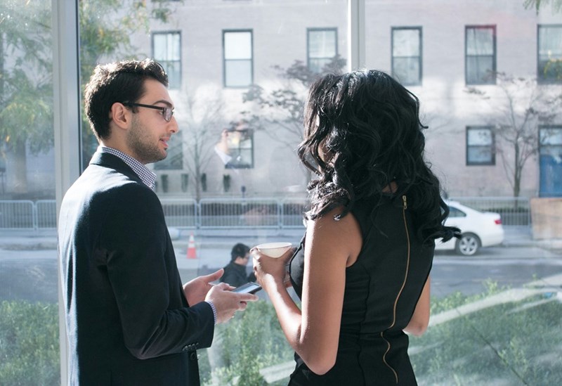 Two coworkers discuss something in front of a window