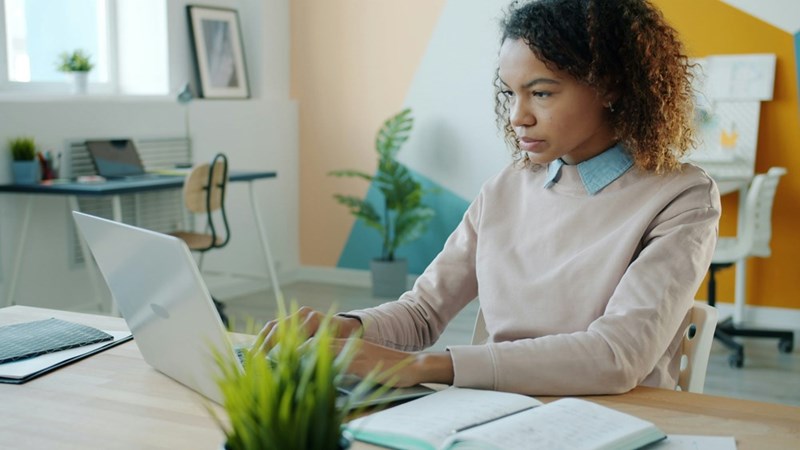 Employee working long hours on a laptop while covering a coworker's workload during his supposed family emergency.