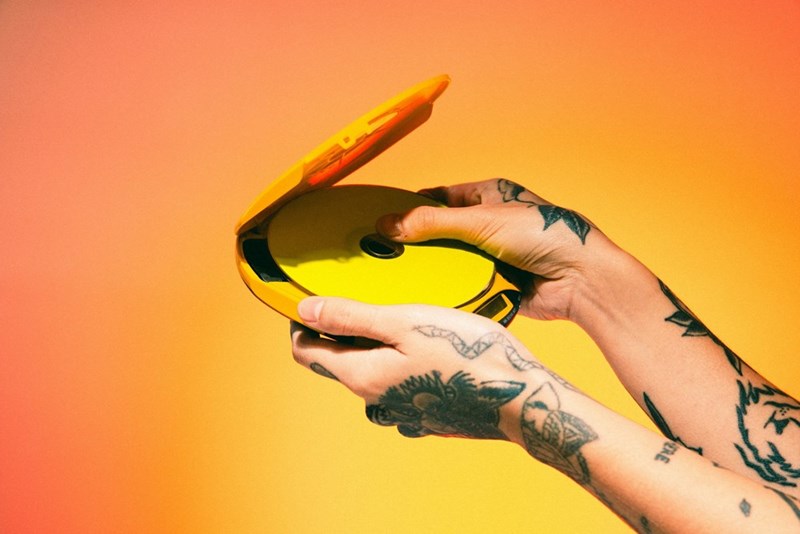 Person placing a CD into a portable CD player.