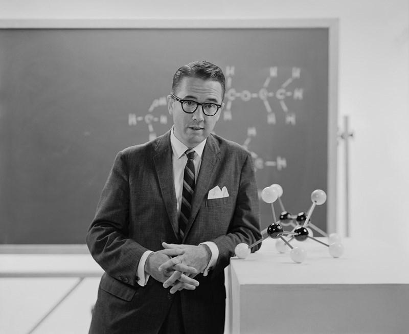 A man in a suit standing in front of a blackboard