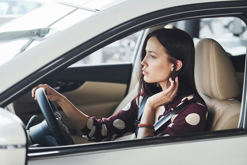 College student sitting behind the wheel of a car.