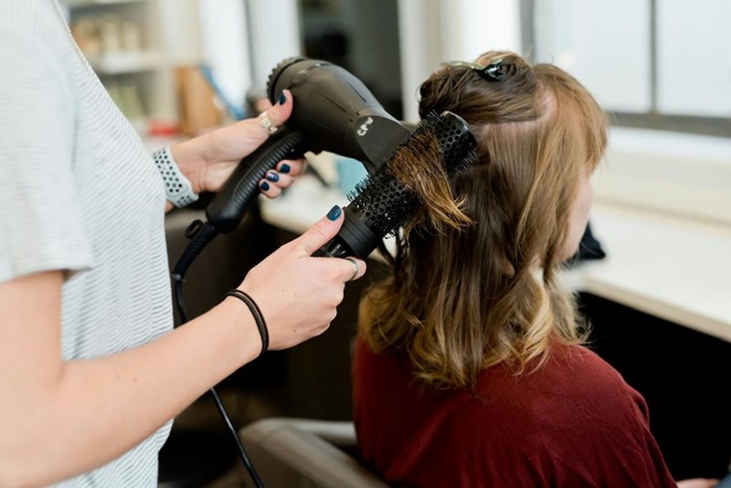 A hairstylist doing a client's hairstyle. Model image.