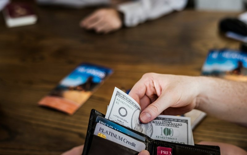 An employee takes cash from a wallet to pay a mandatory onboarding fee.