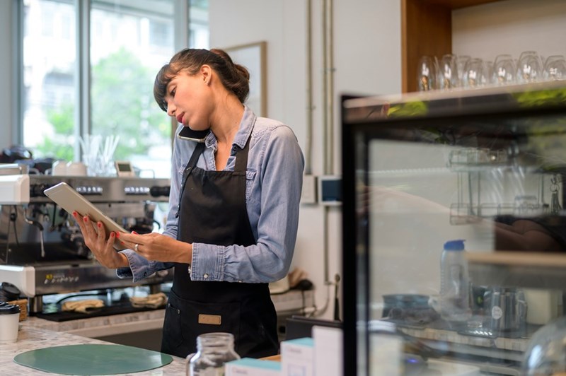 An employee talks on the phone while using a pos system at work