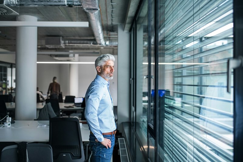 Boss standing in an office, looking out of the window.