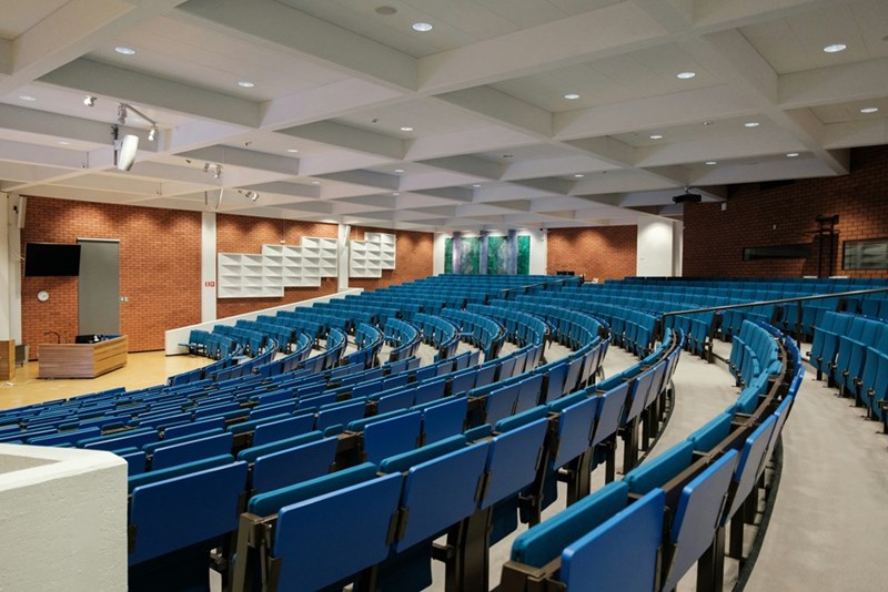 Empty school auditorium with rows of sets and a stage area.