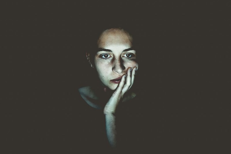 A stressed woman puts her face in her hands