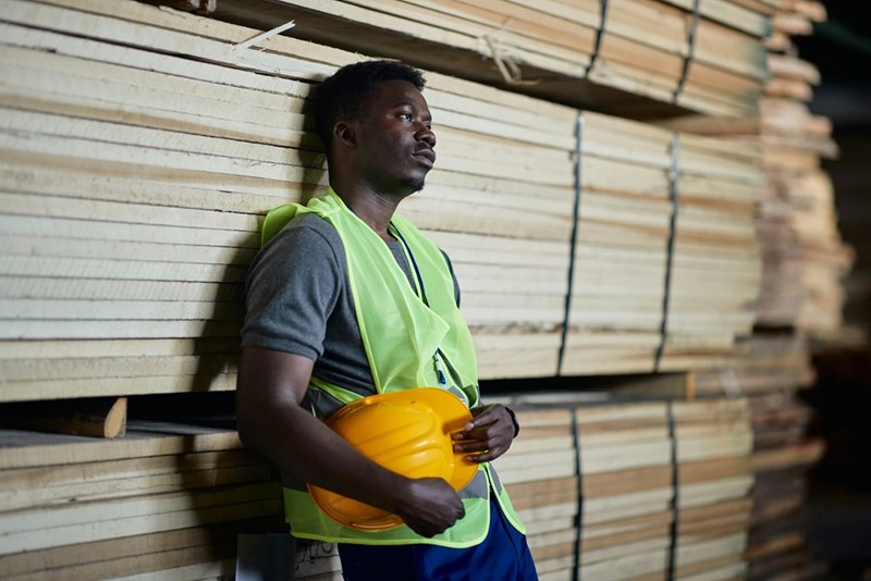 An exhausted worker in hi-vis safety gear takes a moment to decompress.
