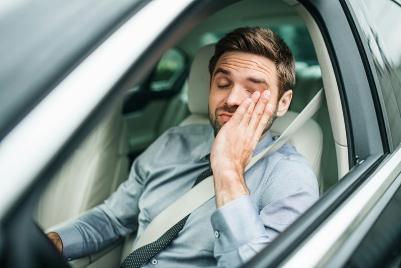 A stressed teacher driving a long commute to work at an elementary school