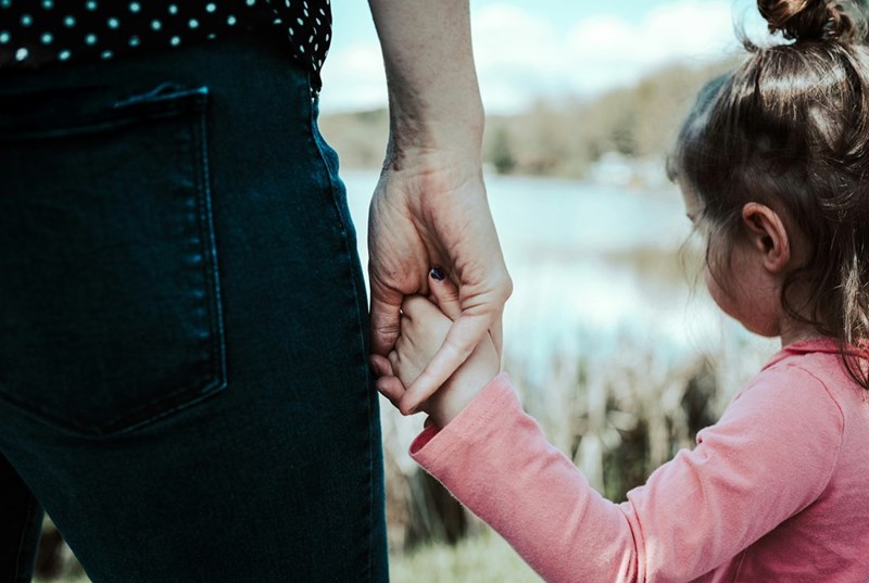 A girl grabbing her mom's hand. Scene shown is a visual representation.