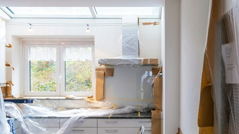 A kitchen with white cabinets in the middle of a renovation.