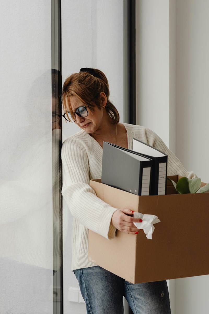 Upset employee packing her belongings after an HR meeting ended with her losing her job.