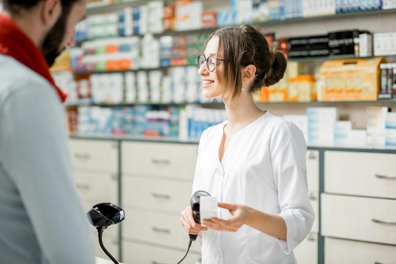 A pharmacy worker scans something at the register