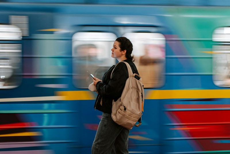 A person stands in front of a moving train on a commute