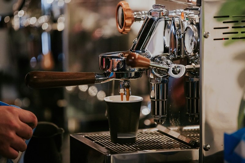 A coffee machine pouring coffee into a cup.