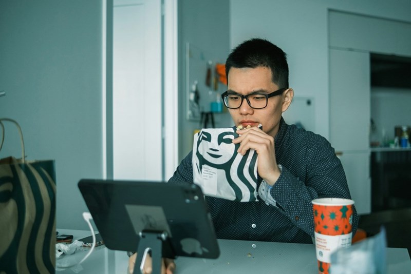 An employee working on his computer while eating lunch. Representation only.