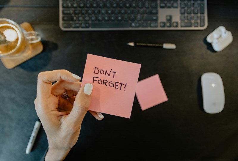 A person holding a note that says “Don't forget”.