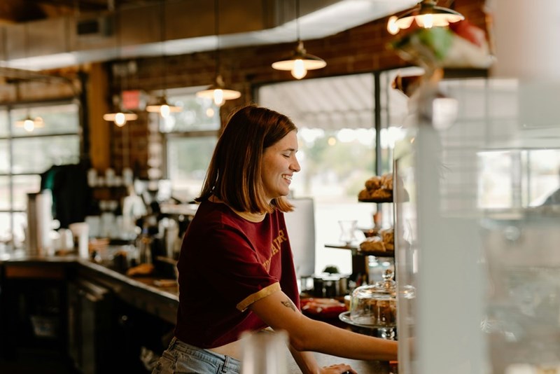A teenage worker serves behind the counter at her job