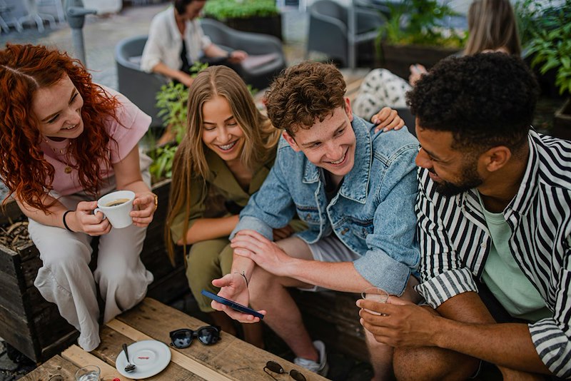 A group of happy young people sitting in outdoor cafe