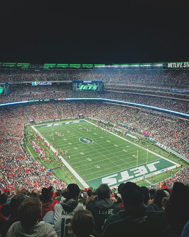 Fans fill a football stadium, representing the game the couple attended with their neighbors' tickets.
