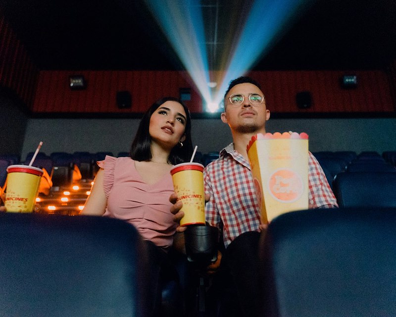 A couple watches a movie together in a movie theater