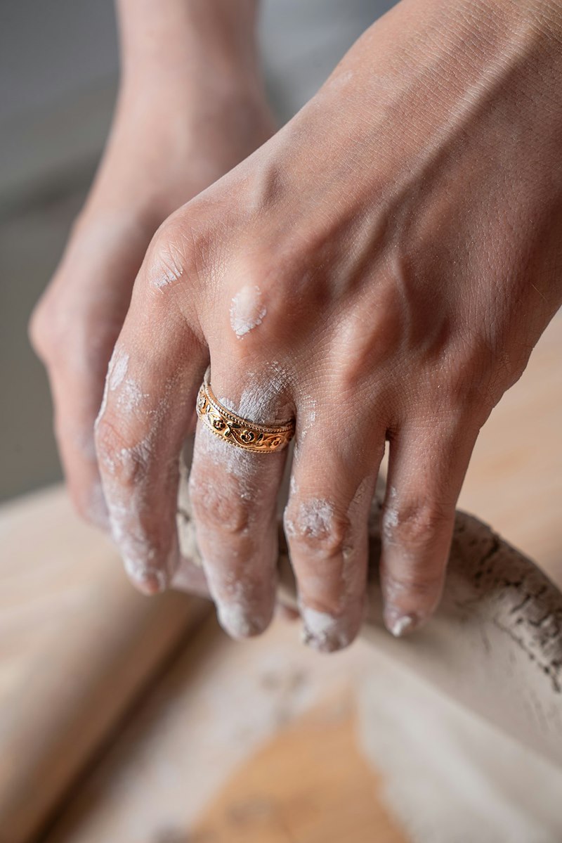 Hands shaping clay on wooden surface