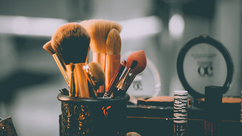 An assortment of makeup brushes and makeup stored in organizers.