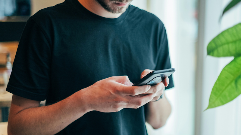 Man in a black T-shirt uses a smartphone