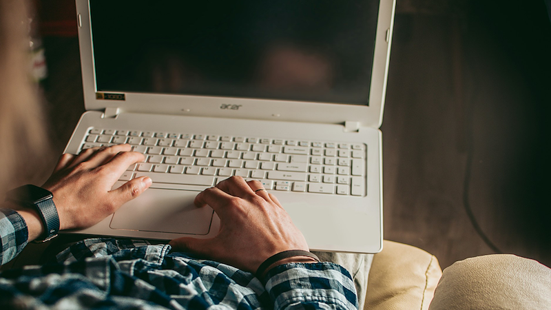 A man checks his email on his laptop while sitting on the couch.