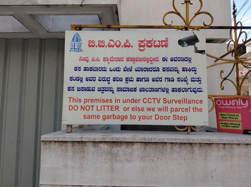 iii ಬಿ.ಬಿ.ಎಂ.ಪಿ. ಪ್ರಕಟಣೆ ನೀವು ಸಿ.ಸಿ. ಕ್ಯಾಮೆರಾದ ಕಣ್ಣಾವಅನಲ್ಲಿದ್ದೀರ. ಈ ಆವರಣದಲ್ಲಿ ಕಸ ಹಾಕಬಾರದು ಒಂದು ವೇಳೆ ಯಾರಾದರೂ ಕಸವನ್ನು ಹಾಕಿದ್ದು ಕಂಡಲ್ಲಿ ಅವರ ವಿರುದ್ಧ ಕಠಿಣ ಕ್ರಮ ಹಾಗೂ ಅವರ ಗಾಡಿ ಸಂಖ್ಯೆ ಮತ್ತು ಕಸ ಬಿಸಾಡುವ ಚಿತ್ರವನ್ನು ಸಾಮಾಜಿಕ ಜಾಲತಾಣಗಳಲ್ಲಿ ಹಾಕಲಾಗುವುದು. This premises in under CCTV Surveillance DO NOT LITTER or else we will parcel the same garbage to your Door Step ownly Food Delivery App Best Food at Best Prices ಉತ್ತಮ ಬೆಲೆಯಲ್ಲಿ ಉತ್ತಮ ಆಹಾರ N