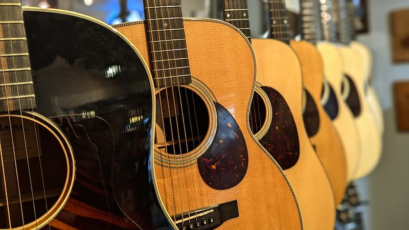 A row of acoustic guitars for sale.