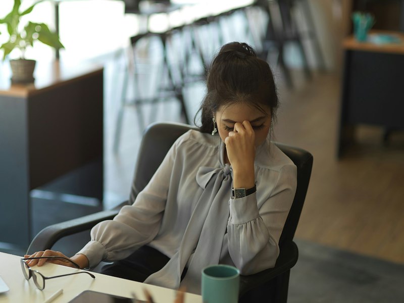 A woman at her desk puts her head in her hands