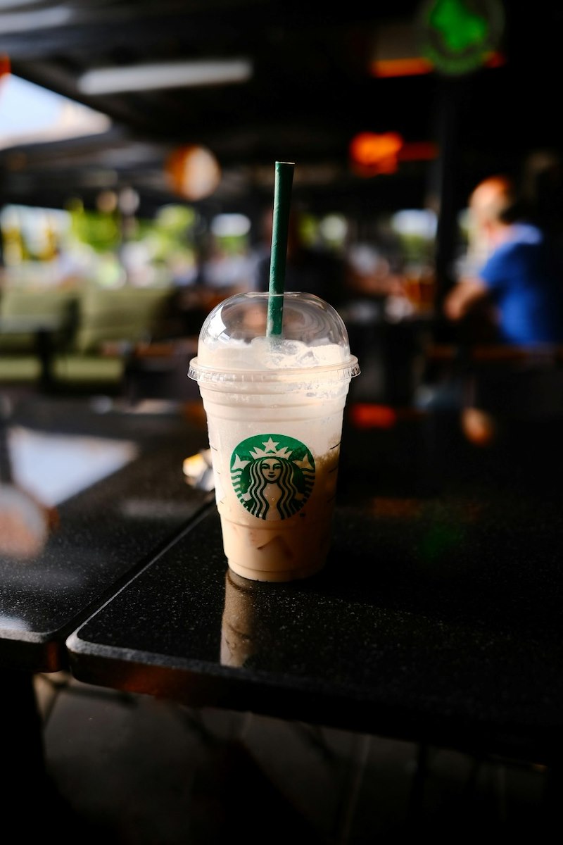 A half-drunk iced takeout Starbucks drink sitting on a table.