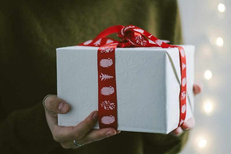 A gift wrapped in white paper with a red ribbon.