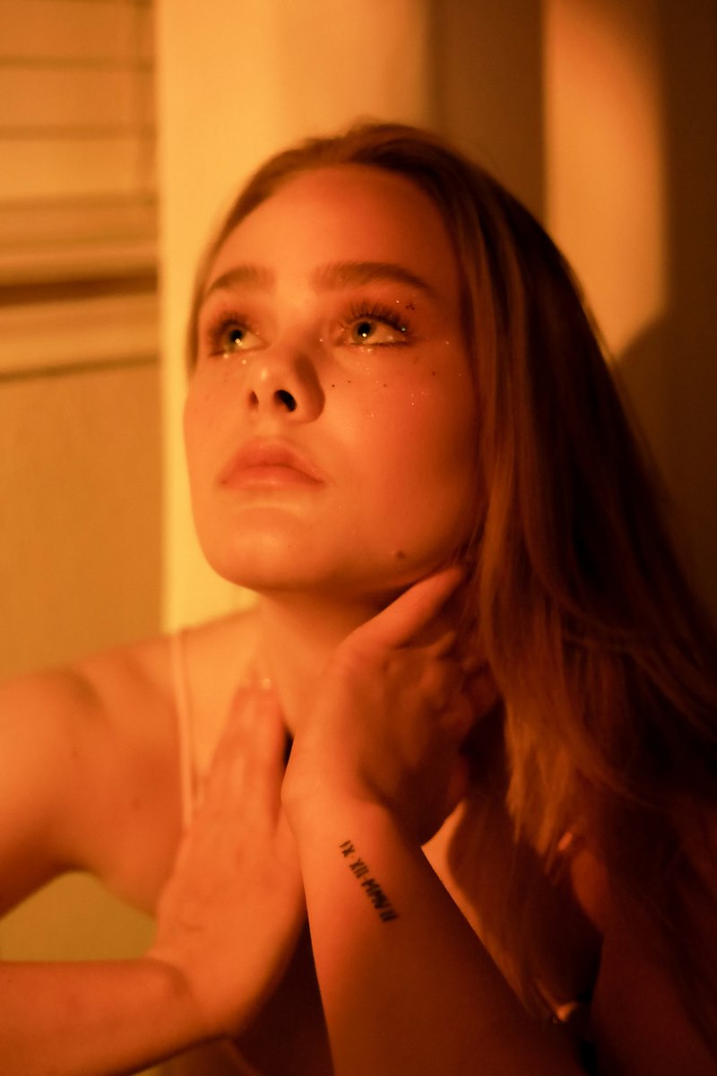 Young woman looks upward with one hand at her neck looking desperate