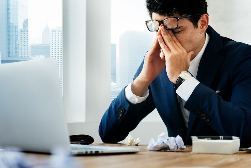 A stressed businessman puts his head in his hands