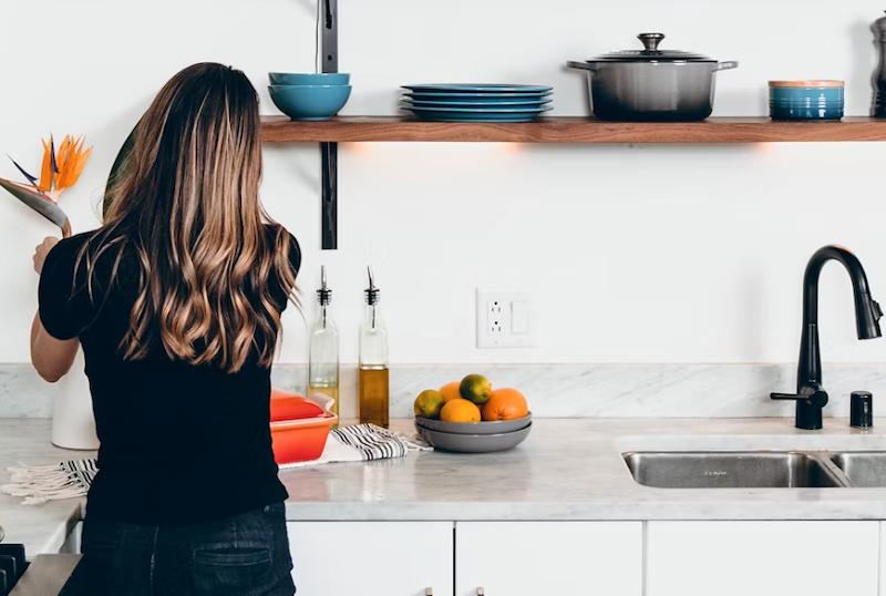 A woman cooks a meal in the kitchen of her rental, where she lives with her landlords.
