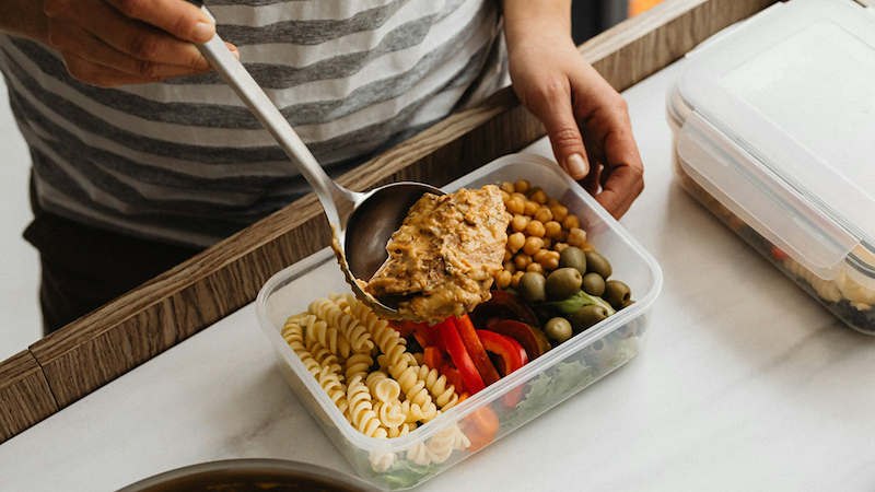 Close-up of a person spooning food into a Tupperware.