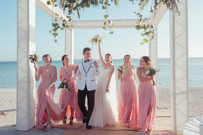 A bride and groom posing with the bridesmaid. Featured likenesses do not identify those mentioned.