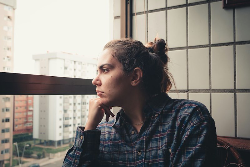 A woman looks out her apartment window.