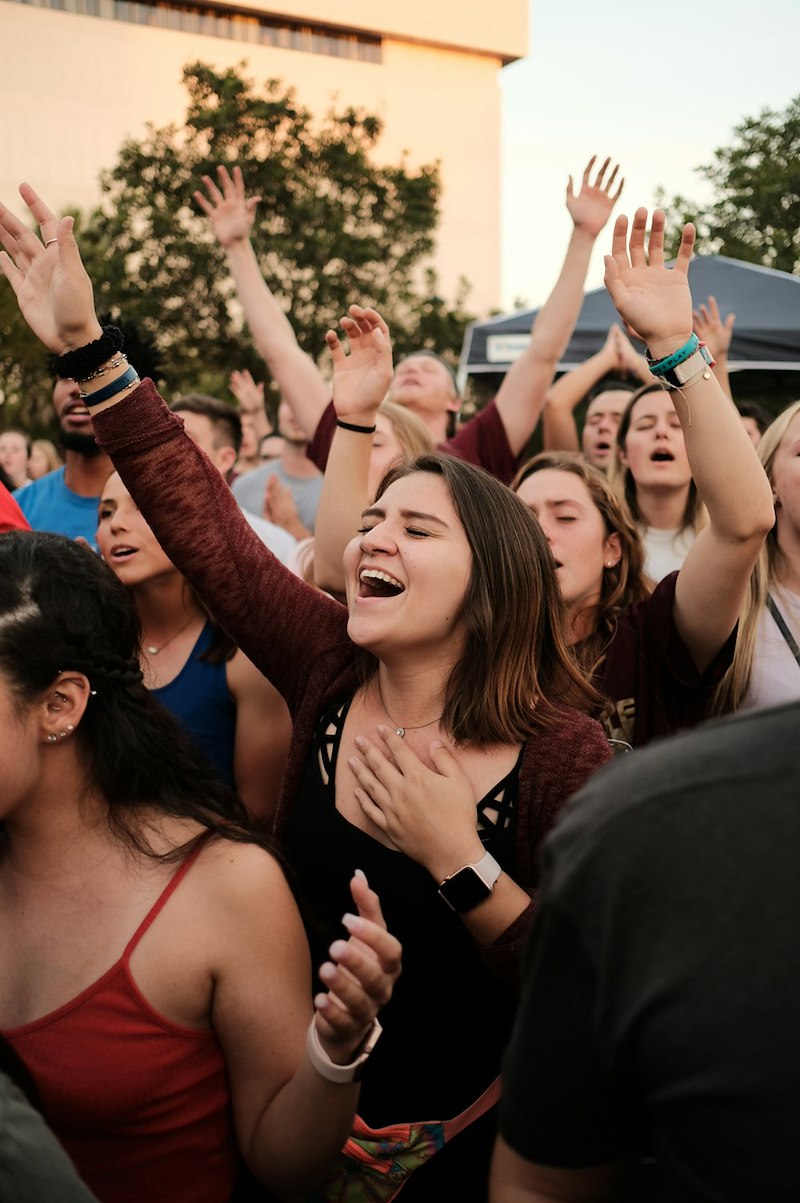 Crowd of people standing while raising their hands