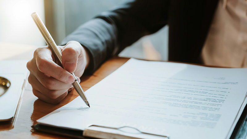 Close-up of an employee signing a contract.
