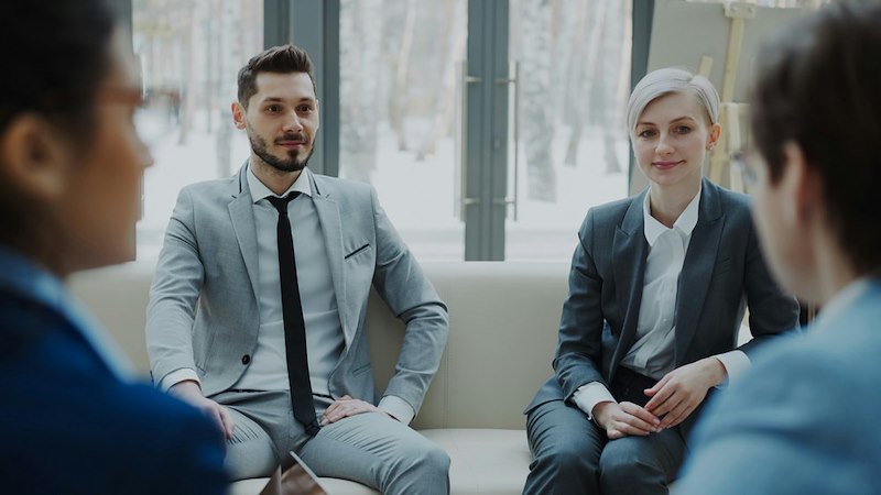 Coworkers sit awkwardly together in the meeting. 