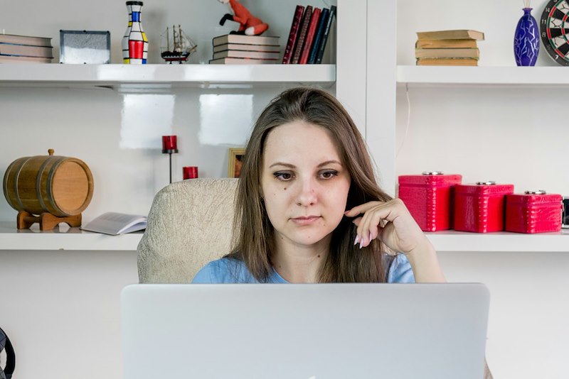 Thoughtful, concerned woman working on a laptop computer, thinking about the complaint.