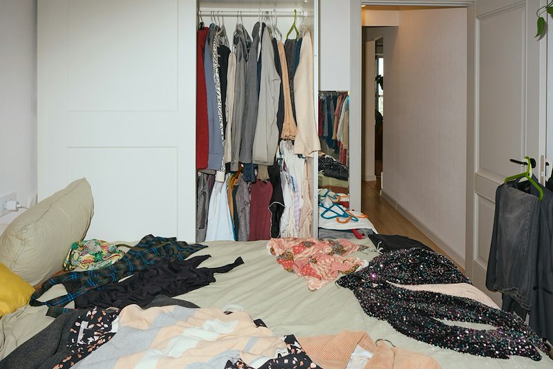 A messy apartment bedroom, clothes strewn about
