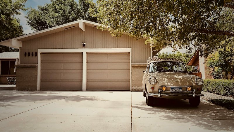 A brown double car garage out behind the house with a car parked in front, like the garage in the rental home.