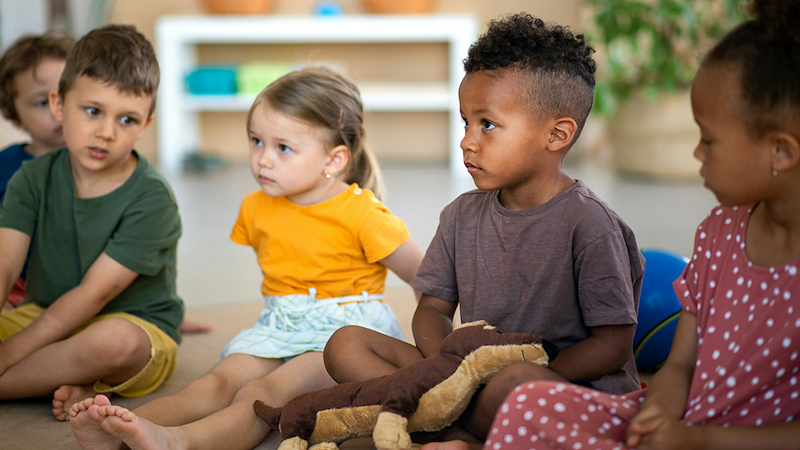 A group of young children sitting on the floor in a daycare.