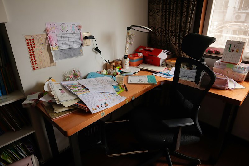 A messy desk with a chair and a laptop